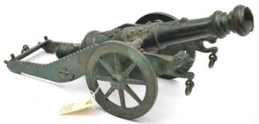 A bronze model of a 17th Century cannon, barrel 17½”, length overall 22½”, the carriage has 2 wheels