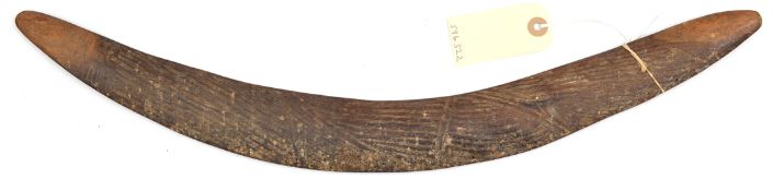 A darkwood boomerang, the rounded side with shallow incised linear panels, the tips and flat