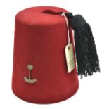 A crimson cloth fez, with tassel, RWAFF badge, silk lining, leather headband with tailor’s name “