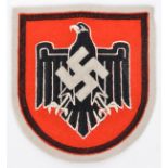 A Third Reich woven felt badge, consisting of a red shield with black border and black eagle with