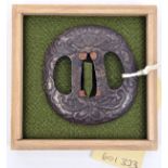 A Japanese tsuba, of unusual dished form, impressed with floral design, in a case. GC