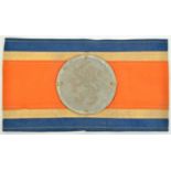 A scarce WWII Dutch Resistance linen armband, in the Dutch colours with sewn on 3” zinc disc