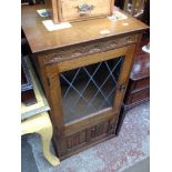AN OAK HI-FI CABINET WITH LEADED GLASS AND LINEN FOLD PANEL DOORS