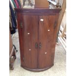 A GEORGE III MAHOGANY BOW FRONT CORNER CABINET WITH PAINTED INTERIOR