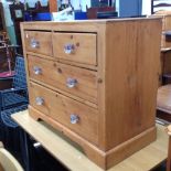 A STRIPPED AND WAXED PINE CHEST OF DRAWERS WITH PRESSED GLASS KNOBS