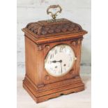 A carved oak mantel clock with brass handle, height 42cm.