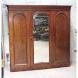 A Victorian mahogany triple wardrobe with central mirrored door flanked by arched panel doors,