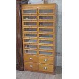 A haberdashery cabinet, light wood with 16 glazed drawers having chrome handles and four lower