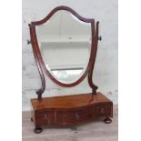 A George III mahogany toilet mirror of shield form on three drawer base.