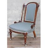 A Victorian walnut nursing chair with carved detail fluted supports and striped upholstery.