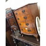 A reproduction burr walnut bow front chest of drawers with vanity lift top.