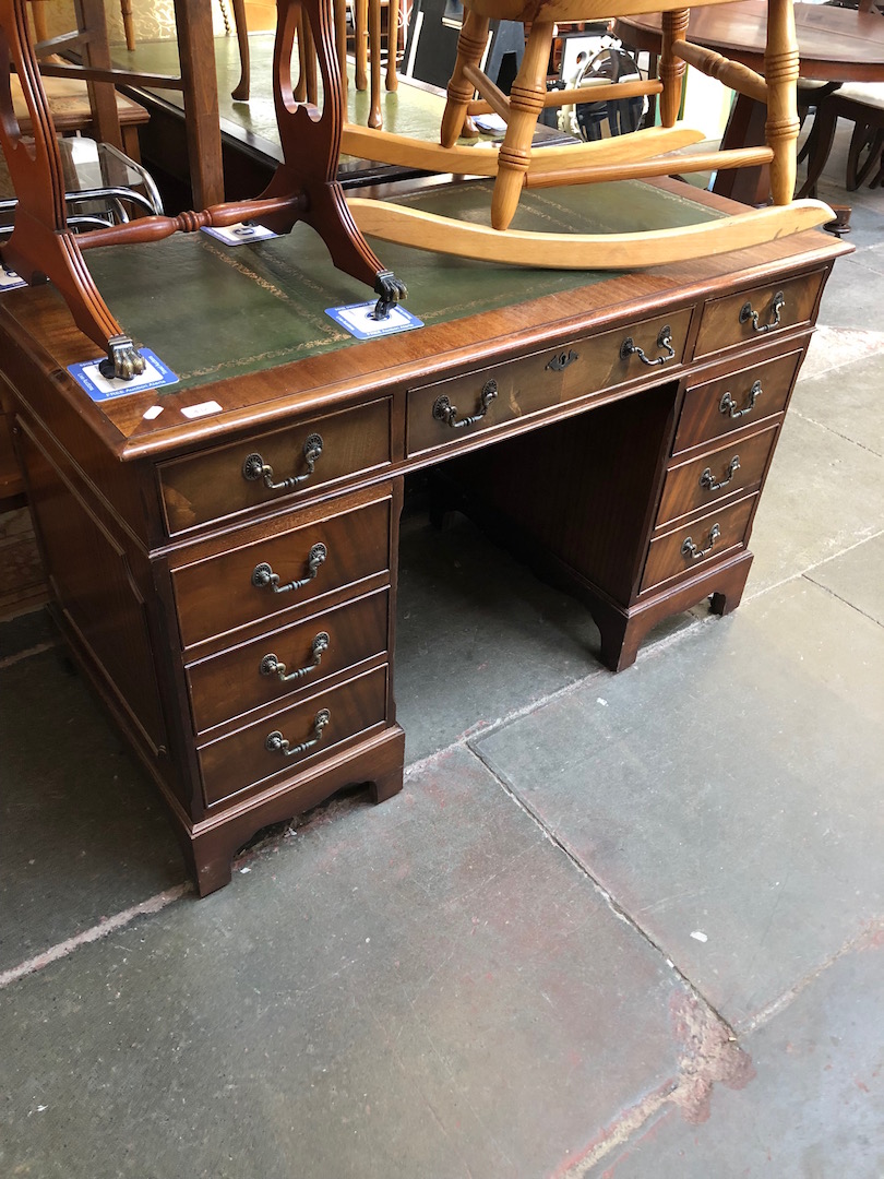 A reproduction leather top pedestal desk.