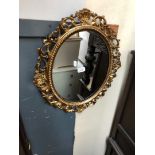 A gilt and carved wood framed oval mirror, 20th Century.