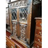 An oak cabinet with carved panels and leaded glass