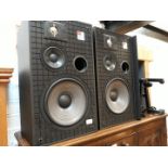 A pair of JBL TLX 9 GI speakers with stands on castors