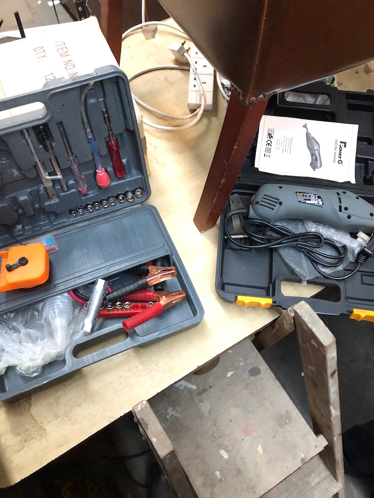 An electric scraper and a toolbox with jump leads, socket set etc