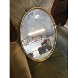 An oval metal framed mirror.