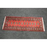 Red ground carpet runner having black and cream decoration with end tassels - 71" x 25.