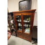 A hardwood two door cabinet with glass shelves.