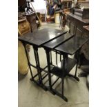 A nest of three ebonised occasional tables on slender turned supports