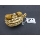 Bone carving of a turtle with two turtles to top of shell