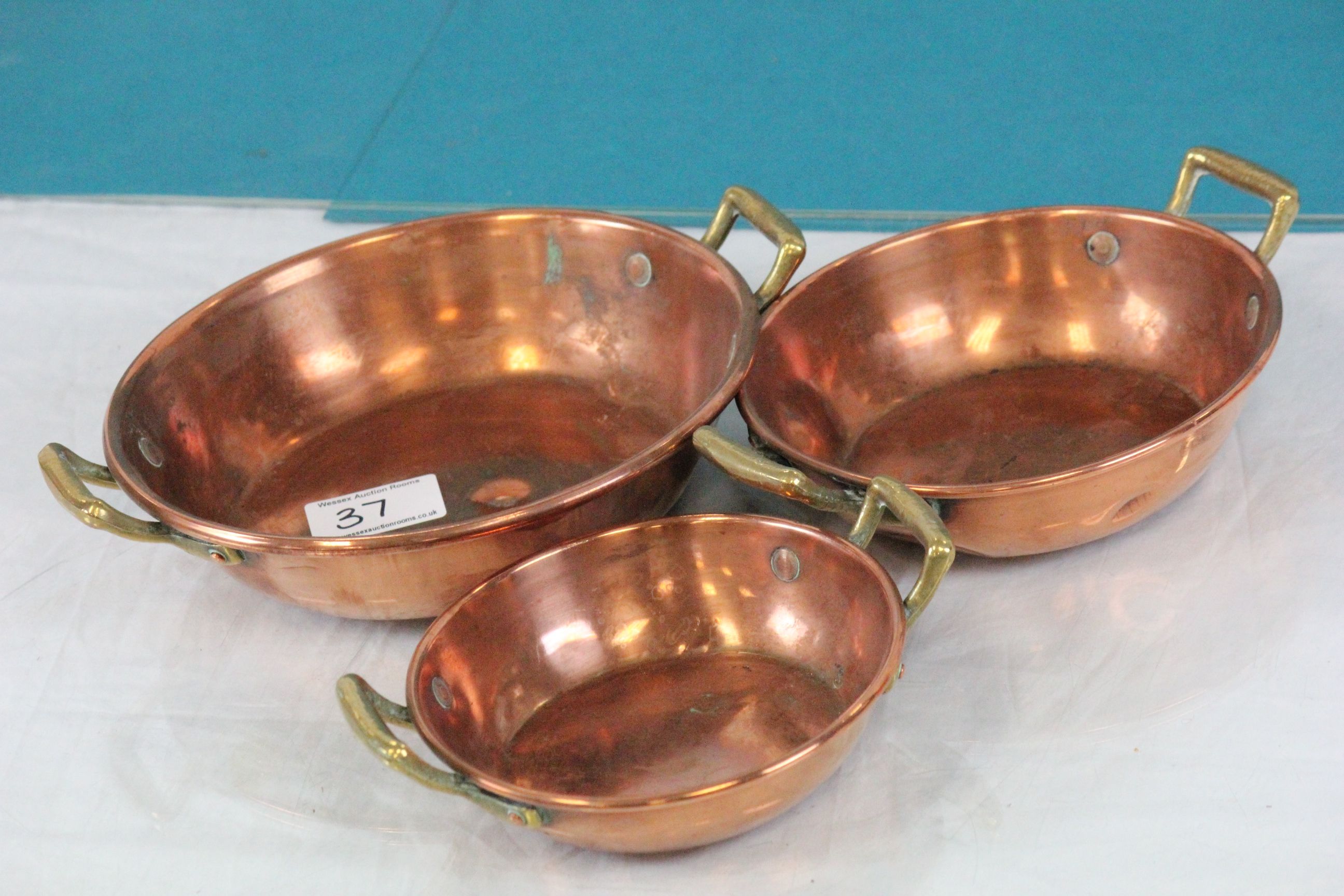 Three Copper Graduating Bowls, each with twin brass handles