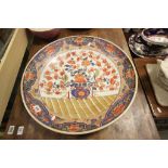 An antique large Japanese charger with Imari decoration with floral panels to edge and floral and