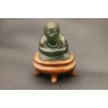 Miniature jade Buddha on wooden stand