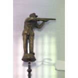 A brass car mascot of a shotgun shooter clay pigeon