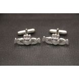 A pair of claddagh style cufflinks with two hands holding a heart