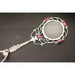 A silver magnifying glass inset with rubies