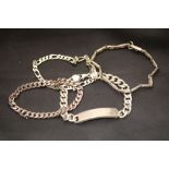 A silver identity bracelet and three others