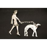 A silver Art Deco style brooch of a lady walking her dog