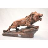 A large spelter and lacquered resin figure of a snarling lion, the base stylised as a rock, carved