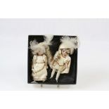 A pair of porcelain miniature dolls, hand painted faces and feet, blue glass eyes, dressed as