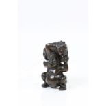 A hardwood carved netsuke of two figures, one supporting the other, height approximately 6.5cm