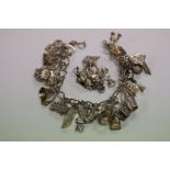 A silver charm bracelet, heart shaped links with approximately 25 charms, some hallmarked together