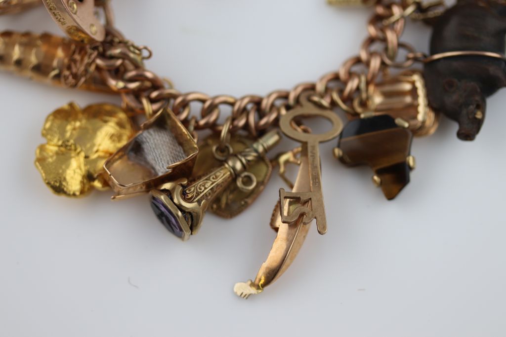 A 9ct gold charm bracelet, the 9ct rose gold padlock clasp curb link bracelet with carved - Image 6 of 8