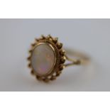 A white precious opal 9ct yellow gold ring, the central oval cabochon cut opal measuring