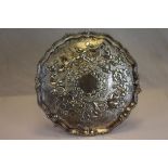 A George III silver salver raised of three ball and claw feet, repousse floral, berry and leaf
