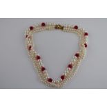 A freshwater pearl and red hard stone three strand necklace, flower head clasp, length approximately