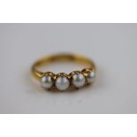 A four stone pearl unmarked gold ring, probably 18ct, claw set pearls, ring size O½