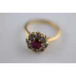 A synthetic ruby and white sapphire cluster unmarked yellow gold ring, the claw set centre round