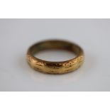 An 18ct yellow gold wedding band, engraved decoration, band width approximately 4.5mm, ring size P½