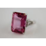 A pink topaz and diamond 9ct white gold ring, the large central four claw set emerald cut pink