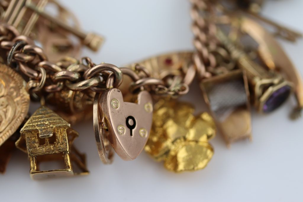 A 9ct gold charm bracelet, the 9ct rose gold padlock clasp curb link bracelet with carved - Image 4 of 8