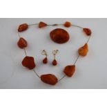 An early 20th century butterscotch amber suite comprising amber necklace, amber brooch and amber 9ct