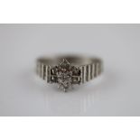 A diamond 18ct white gold flower head cluster ring, seven illusion set eight cut diamonds with