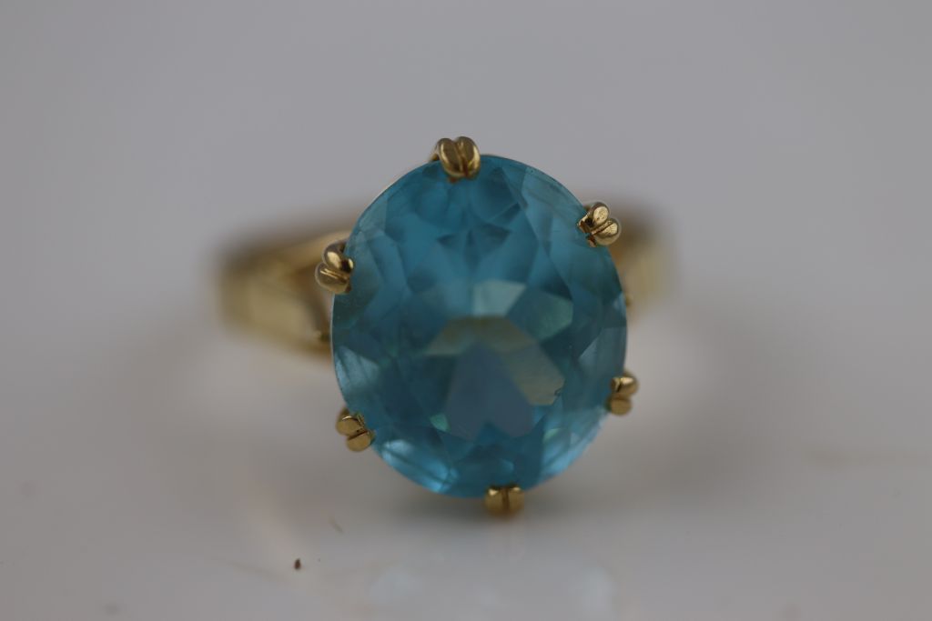 A blue topaz 18ct yellow gold ring, the claw set oval mixed cut blue topaz, measuring approximately