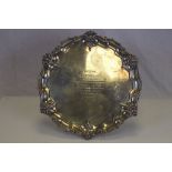A Victorian silver presentation salver raised on three scroll feet with stylised shell and scroll